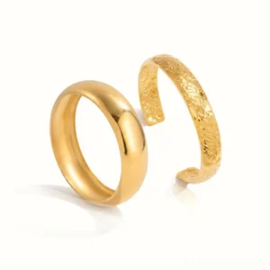 18K gold bangle set flat lay top-down view white background showing smooth cuff and open engraved floral pattern warm gold tone