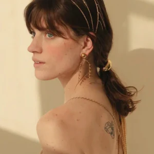 Woman wearing 18K gold tassel earrings side profile view elegant drop design worn on ear