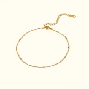 18K gold beaded satellite anklet with spacer beads flat lay on neutral background, showing full adjustable length