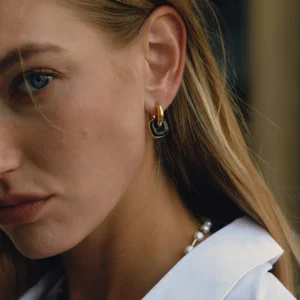 18k gold black enamel drop hoop earrings on blonde model portrait close-up wearing pearl necklace