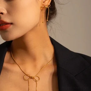 18K gold bow dangle earrings styled on model with matching bow lariat necklace closeup