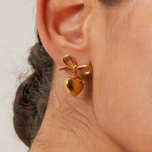18K gold bow heart drop earrings on ear close-up side view model wearing elegant hairstyle