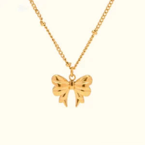 18K gold bow necklace with delicate satellite chain flat lay on plain background - polished gold finish with 3D textured bow pendant