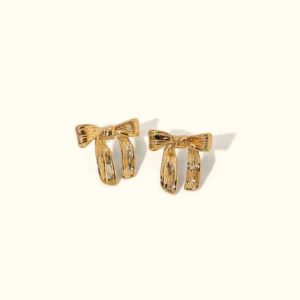 18K gold bow stud earrings flat lay top-down view plain background polished gold ribbed design