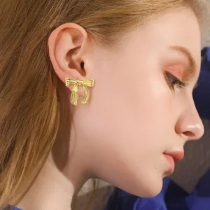 18K gold bow earrings worn on model profile close-up shot delicate feminine style