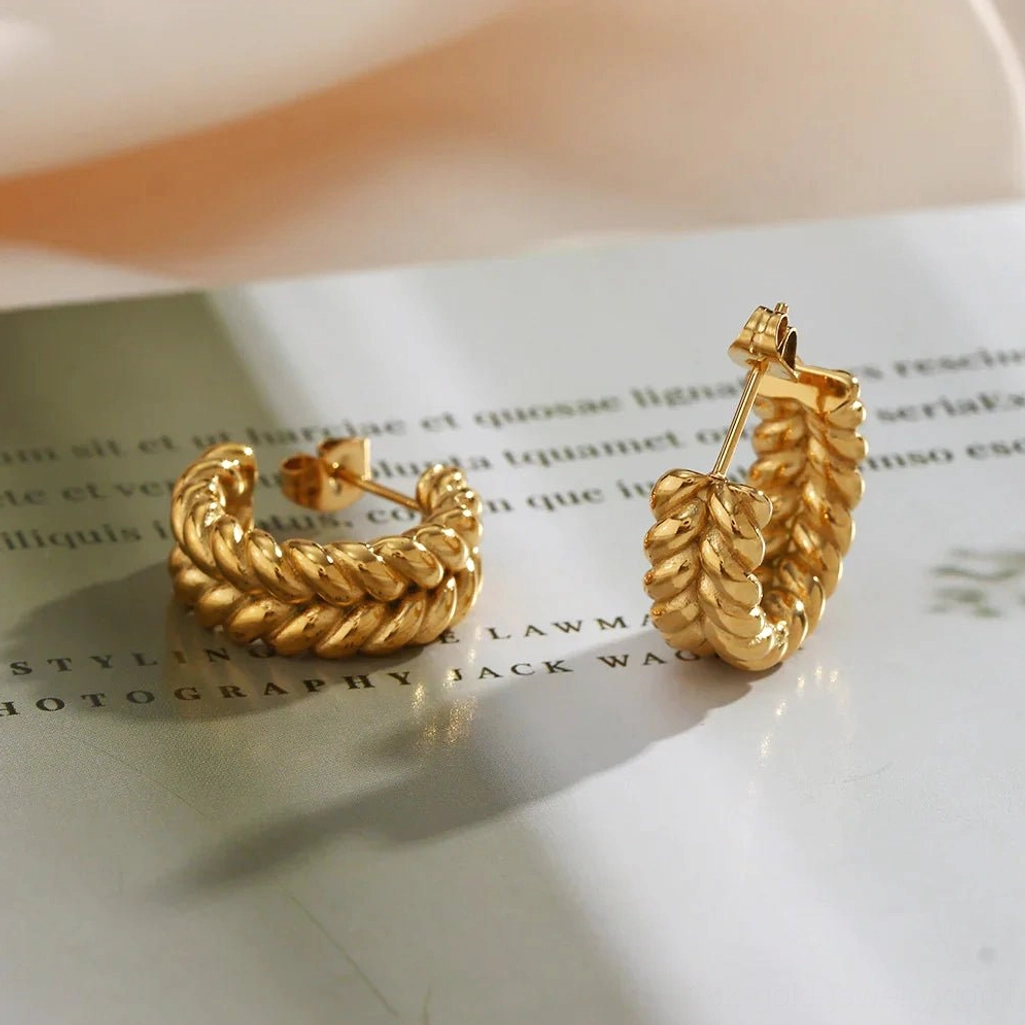 Side back view of 18K gold braided hoop earrings on magazine background showing earring post and twisted braided construction
