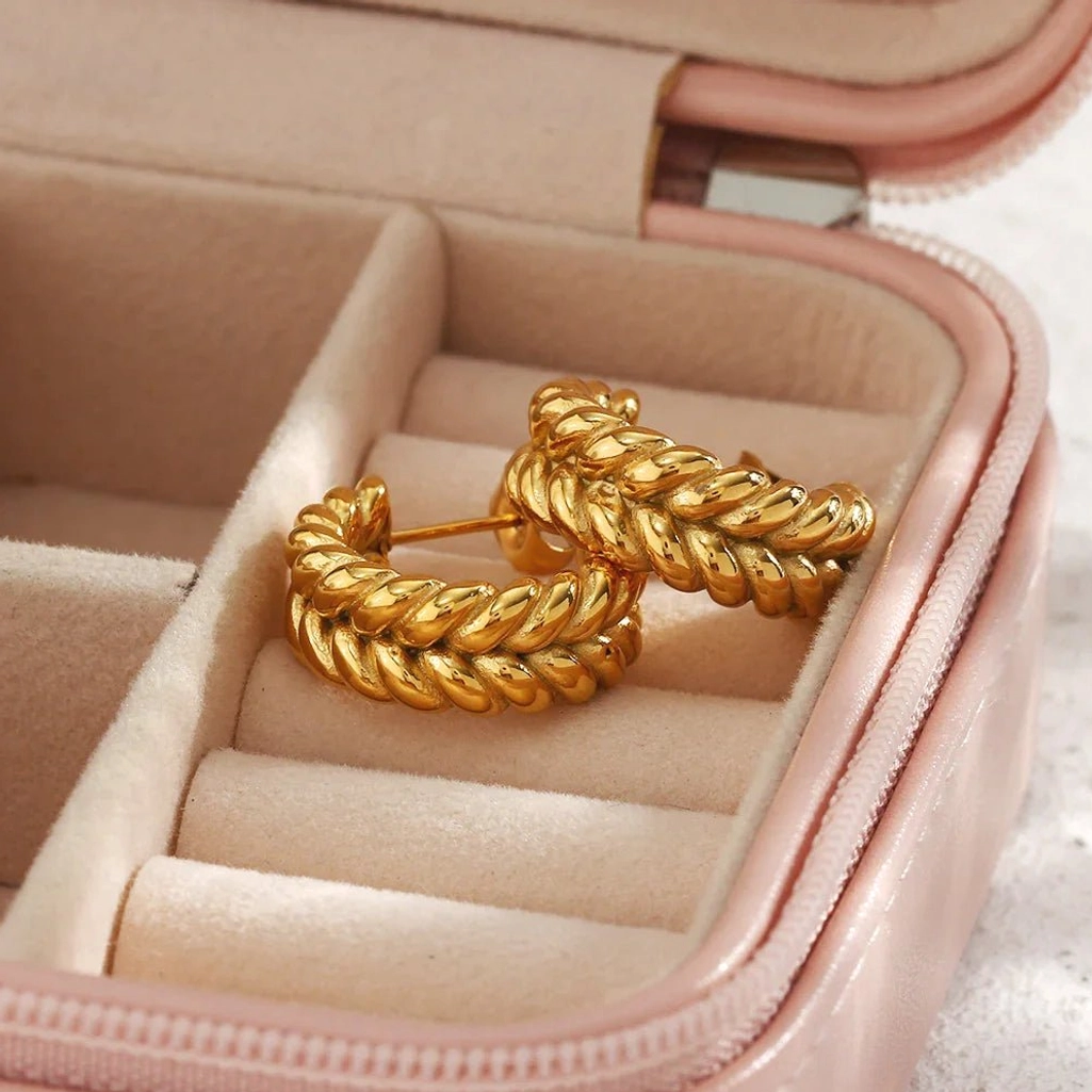18K gold braided hoop earrings top-down flat lay in jewelry storage box showing twisted braided design and metal shine