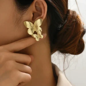 18K gold butterfly stud earrings worn on model ear close-up side view showing elegant wearing effect with hand touch detail