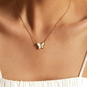 18K gold butterfly pendant necklace worn on female neck, dainty chain at collarbone, model wearing white spaghetti strap top, close-up detail view of delicate jewelry