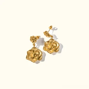 18K gold camellia drop earrings flat lay top-down view showing dual flower petals design with polished golden finish on off-white background