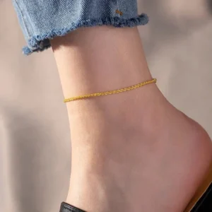 Model wearing slim gold chain anklet on ankle with cropped denim jeans close-up side view