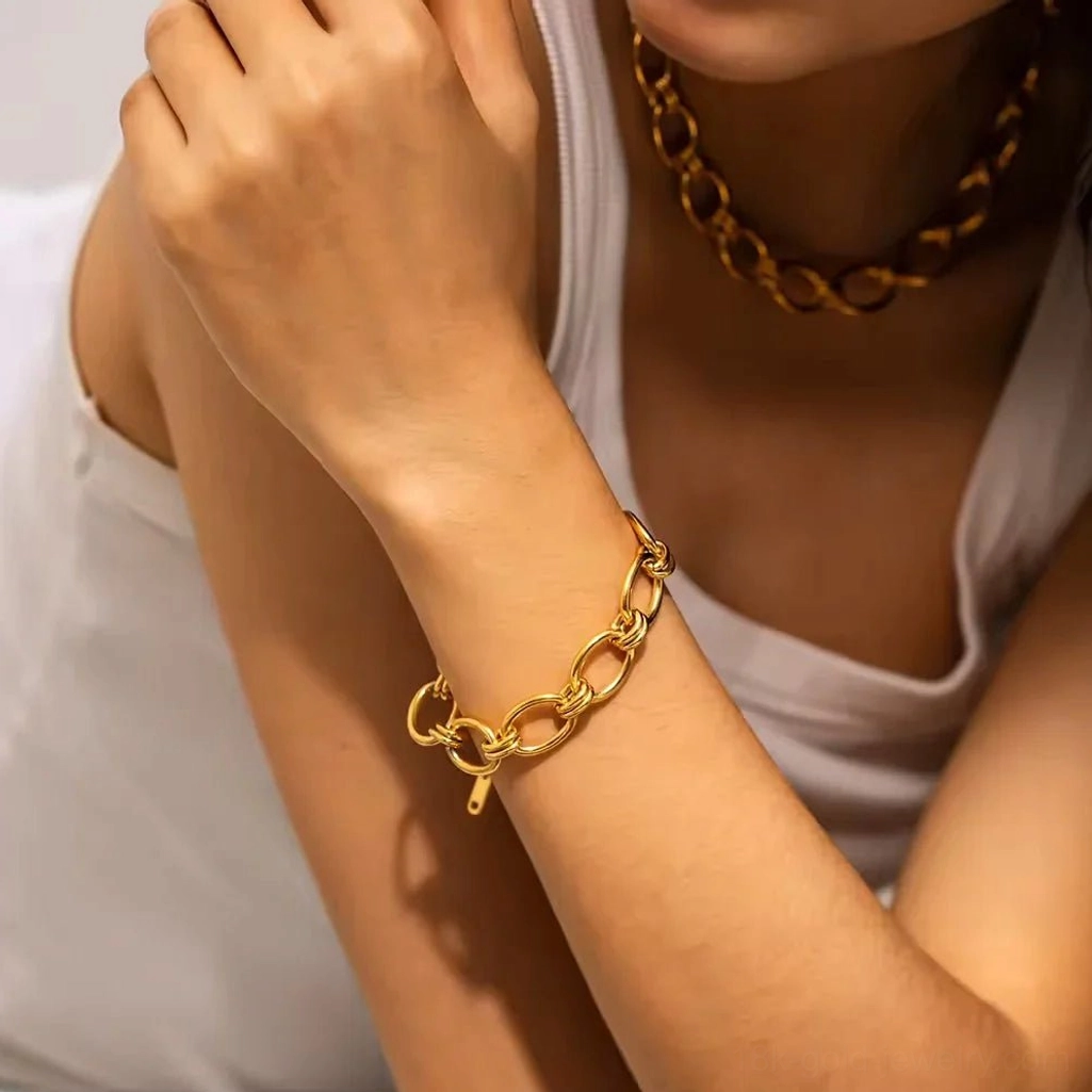 18K gold chunky chain bracelet on female wrist indoor casual white tank top oval link lobster clasp