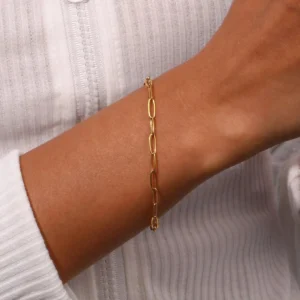 Gold chain bracelet on wrist close-up side view worn on model with white top