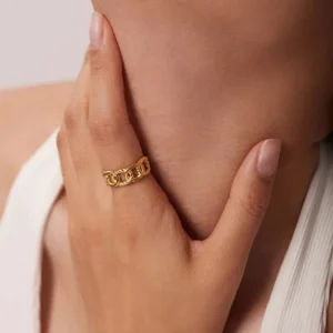 18K gold chain link ring worn on model's index finger - close-up partial shot displaying chunky gold tone chain band with sophisticated styling