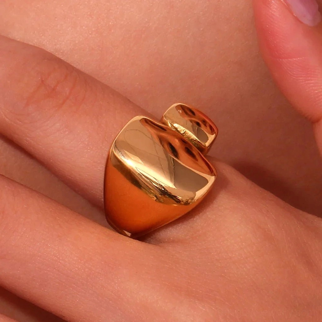 18K Gold chunky geometric ring with rounded irregular shape on female model hand, close-up finger shot showing high-shine warm gold reflective surface