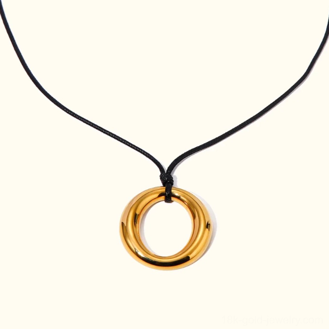 18K gold open circle pendant necklace flat lay front view with polished gold ring charm and black waxed rope cord on light background