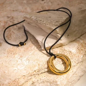 18K gold open circle pendant necklace side view showing adjustable black waxed cord with warm gold tone and natural stone texture background