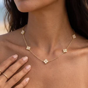 Delicate 18K gold clover station necklace worn on woman with dark hair, close-up neck portrait showing crystal charm details against skin, elegant styling