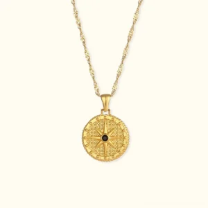 18K gold compass pendant necklace flat lay front view with twisted chain and central black stone accent on neutral background