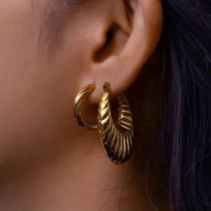 Close-up side view of 18K gold textured hoop earrings worn on ear, showing ridged surface detail and warm gold finish