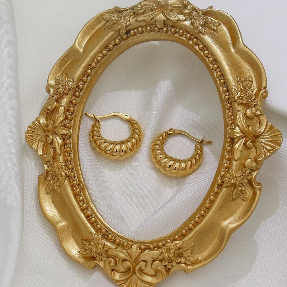 18K gold croissant hoop earrings flat lay with vintage gold frame and satin background