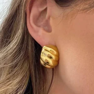 18K Gold Croissant Huggie Earrings worn on model ear close-up, demonstrating secure fit and shiny textured surface against skin