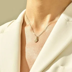 Model wearing gold croissant pendant necklace layered with multiple chains on chest and neck