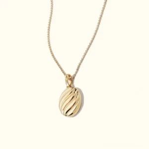 Gold twisted croissant pendant necklace flat lay with polished metal texture and cable chain
