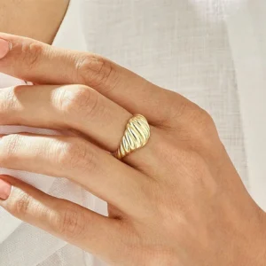 Gold croissant ring worn on hand side view close-up showing ribbed twisted texture