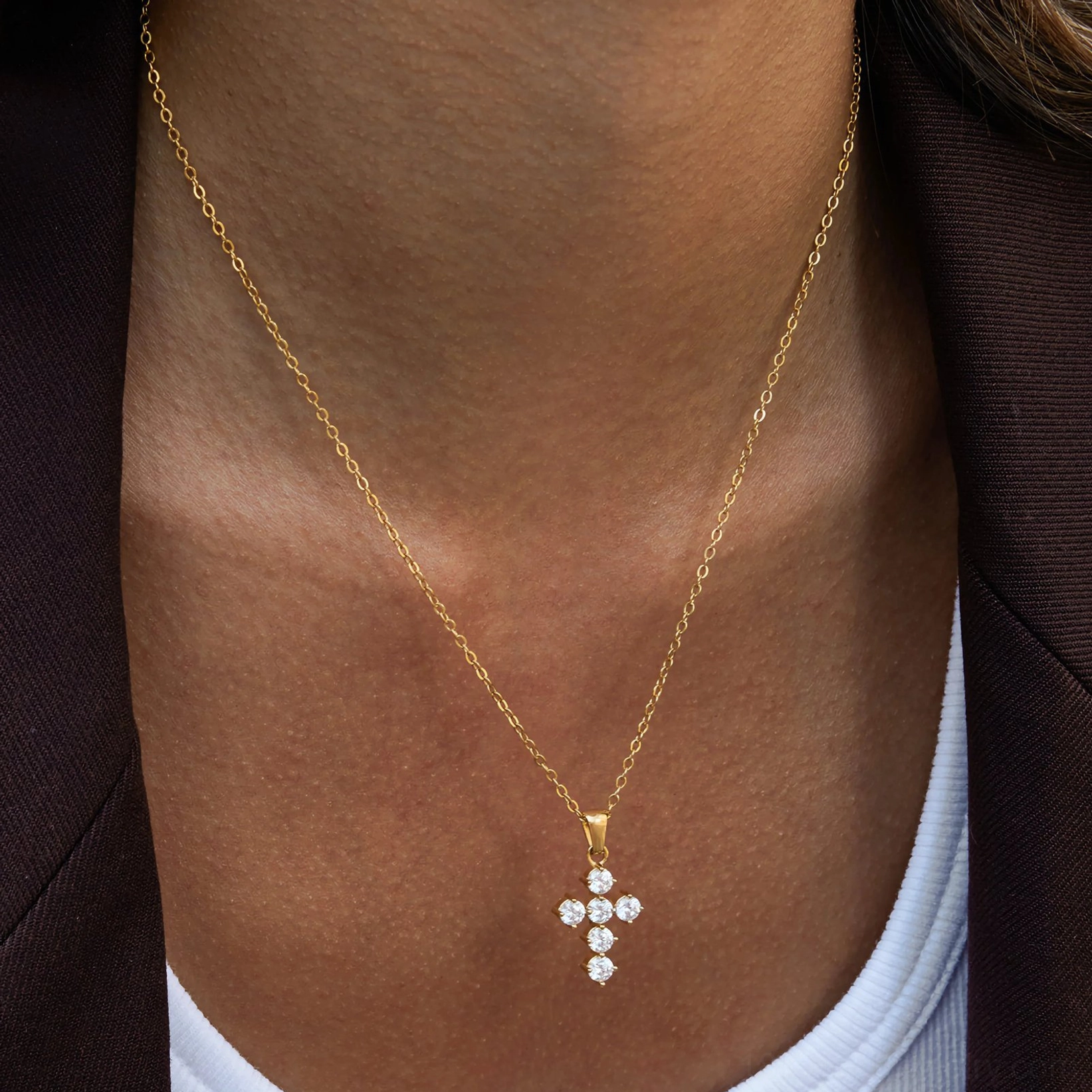 minimal gold cross diamond necklace on dark skin tone model showing elegant collarbone styling and pendant sparkle