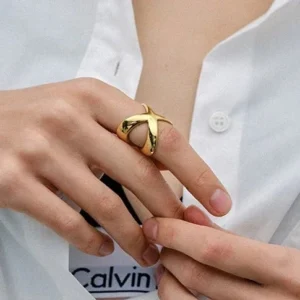 18K gold cross ring worn on model index finger close-up hand shot sleek polished gold styling
