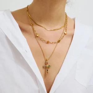 Layered 18K gold cross necklace worn on woman neck model close-up view colored crystal