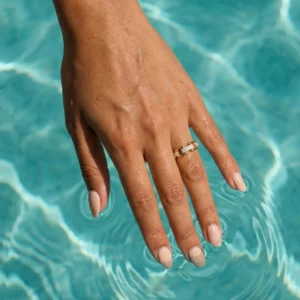 18K gold crystal ring worn on hand in pool water demonstrating water resistant jewelry for active lifestyle