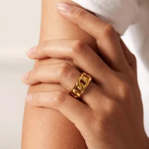 Cuban link gold ring worn on female hand close-up side view chunky band warm golden tone