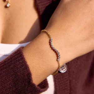 18K gold diamond bracelet worn on female model's wrist close-up detail view with burgundy knitwear