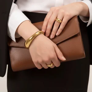 18K gold open cuff bangle bracelet worn with stacked rings on female hands business formal styling layered jewelry