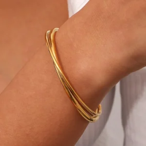 18K gold open cuff bangle worn on woman's wrist, forearm side view showing sleek layered twisted design with snug comfortable fit