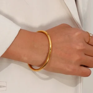 18K gold open cuff bangle on female model wrist side view with ring elegant styling beige blazer