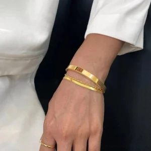 18K gold cuff bracelet worn on wrist stacked with thin chain close-up side view luxury jewelry
