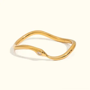 18K gold curved bangle with marquise crystal accent, flat lay overhead view on plain background showing organic wave design and polished finish