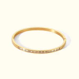 18K gold diamond baguette bangle with hinged open cuff design and cubic zirconia accents on plain background