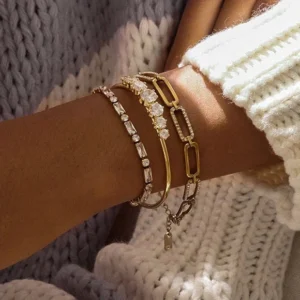 18k gold layered diamond bracelets stacked on female wrist with knitted sweater showing three-piece set styling