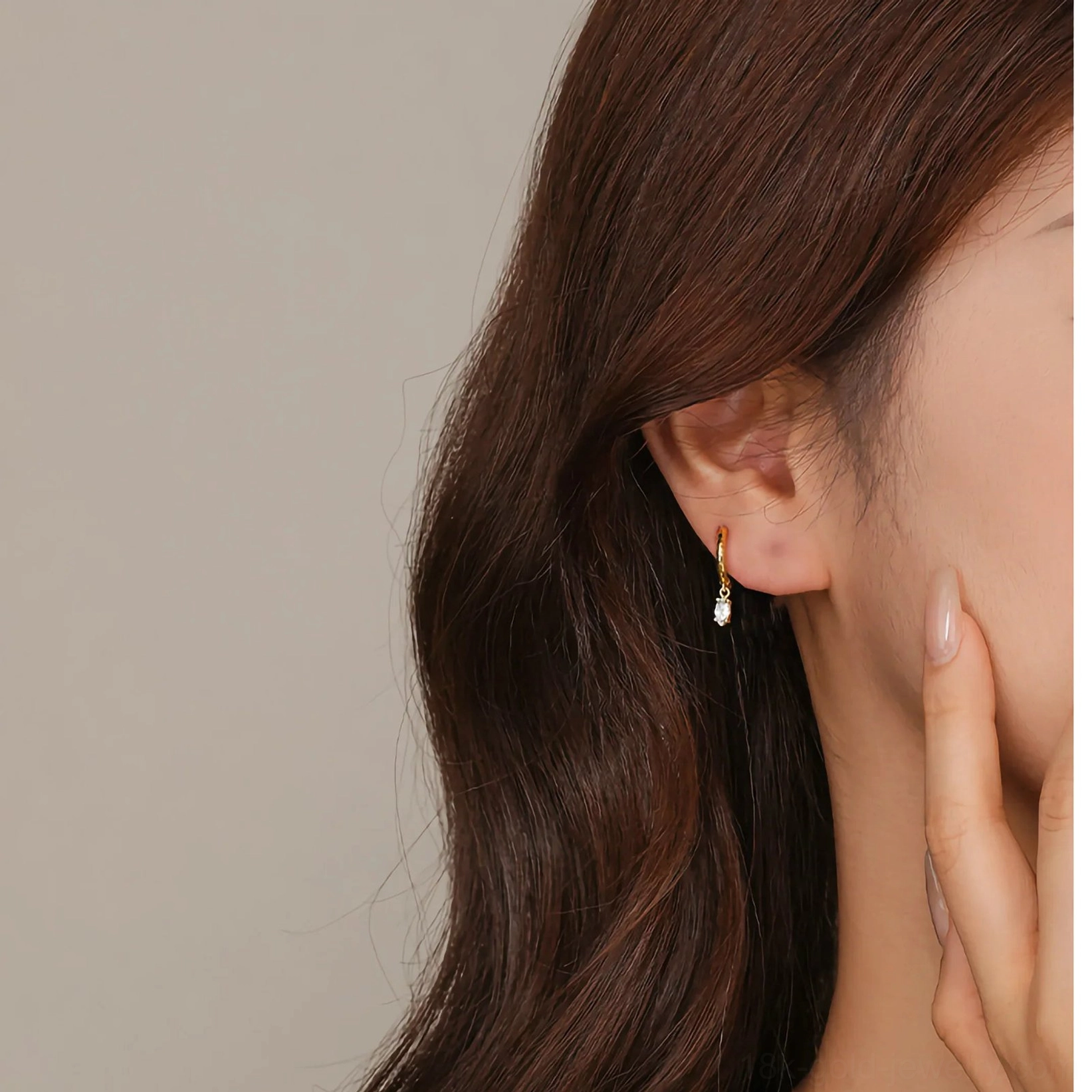 Side back view of 18K gold diamond drop huggie earring worn on female model showing minimalist hoop with small dangling CZ drop