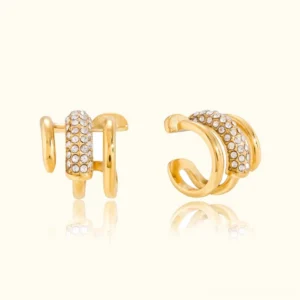 18K gold layered diamond ear cuff and stud set flat lay featuring double hoops with pavé crystal embellishments and delicate studs on off-white background