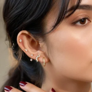 18K gold diamond stud earrings worn on model's ear close-up side view showing layered ear piercing stack with cubic zirconia stones