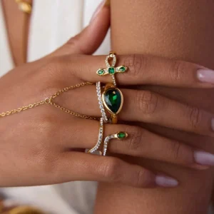 Stacked 18K gold rings with hand chain worn on female model's arm - close-up lifestyle view featuring layered gemstone jewellery