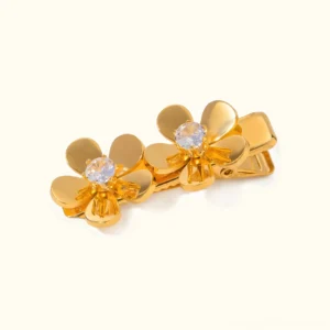 18K gold flower hair clips flat lay top view featuring polished gold petals with central cubic zirconia gemstone on plain background