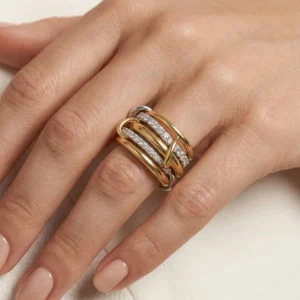 Two-tone 18K gold interlocking diamond ring worn on female model hand with nude manicure showing comfortable fit