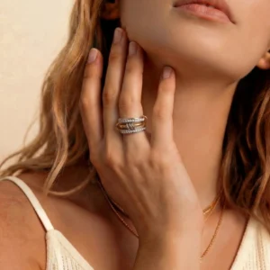 Woman wearing two-tone 18K gold diamond ring stacked on middle and ring finger, close-up upper body shot showcasing ring on hand