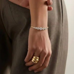 18K gold tennis bracelet on woman's wrist, side view showing full row of sparkling cubic zirconia diamonds with grey formal styling